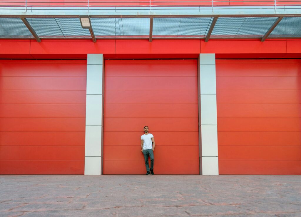 Man portrait leaning on a red warehouse door