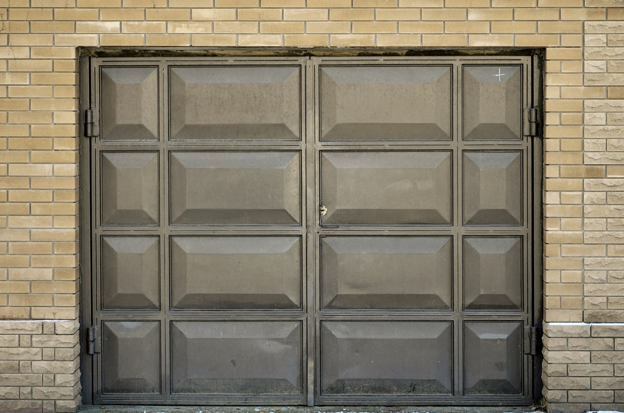 The texture of a painted metal gate from a brick garage